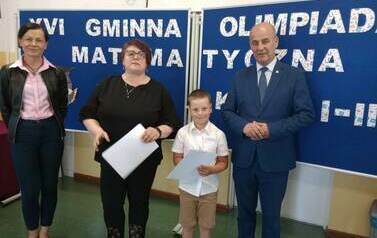 Uczeń prezentuje nagrodę zdobytą w konkursie matematycznym wraz z W&oacute;jtem i Panią Dyrektor