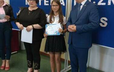 Uczennica prezentuje nagrodę zdobytą w konkursie matematycznym wraz z W&oacute;jtem i Panią Dyrektor